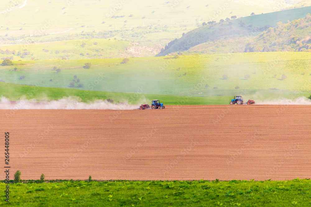 Obraz premium Dust from a tractor working in a field in spring
