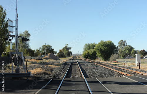 Fototapeta double level Railway crossing over a tar road in an industrial area in a small t