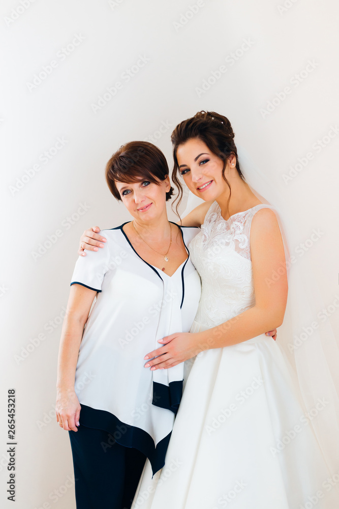 mom and bride hug and look at the camera. festive clothing