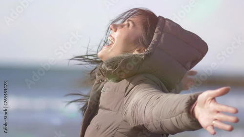 Happy young woman feeling freedom turning around in front of the ocean slow motion