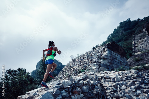 Fitness woman trail runner running at great wall on the top of mountain
