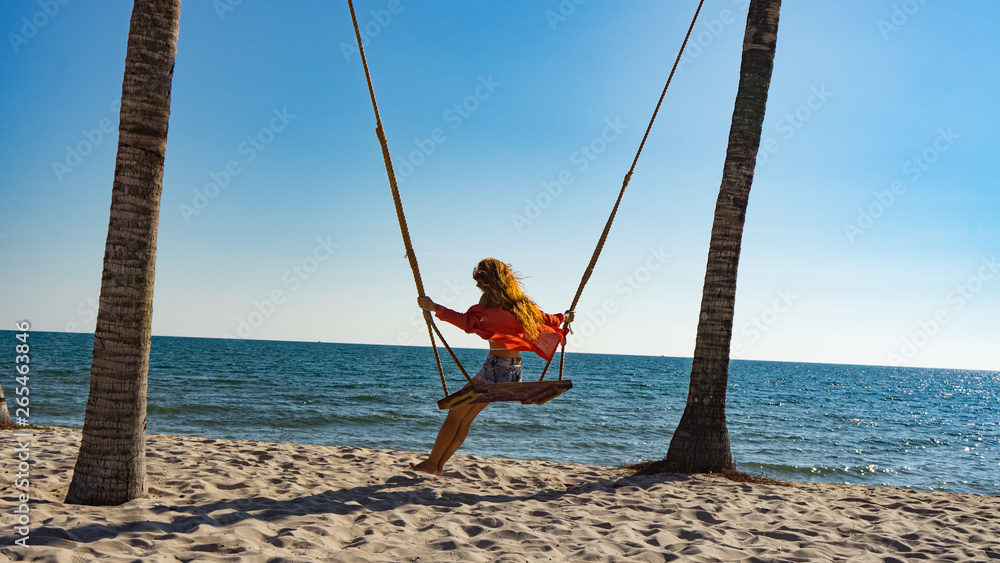 Vacation concept. Young woman swing on a beach swing. Happy traveller women on the Phu Quoc beach