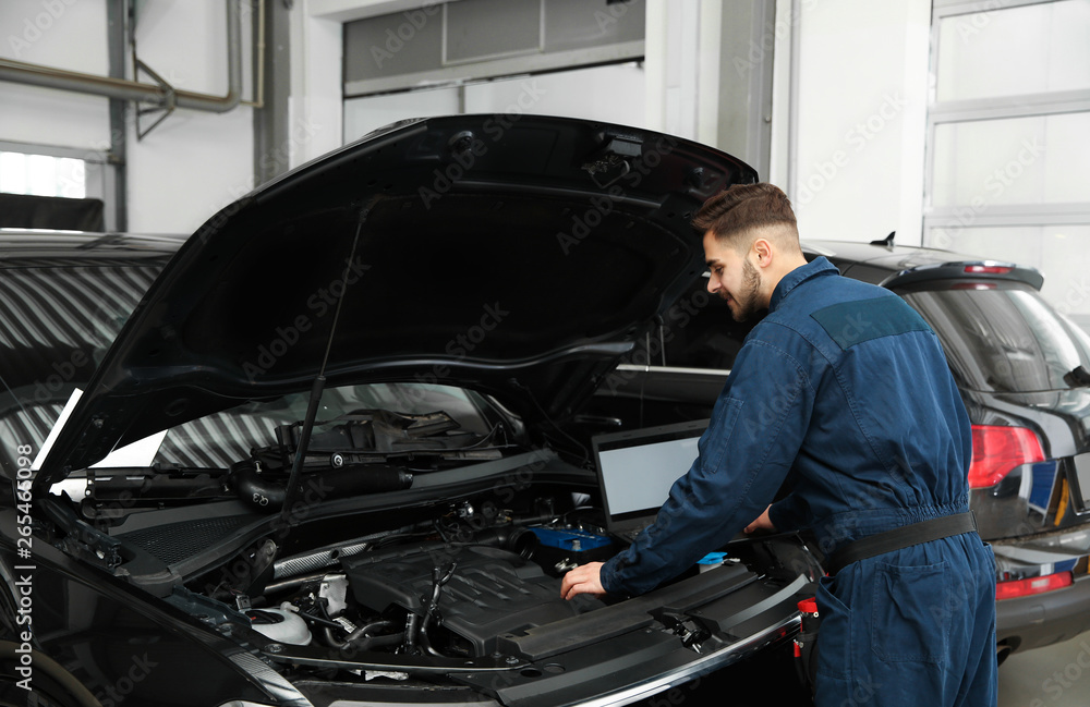 Technician checking car with laptop at automobile repair shop Technician checking car with laptop at automobile repair shop