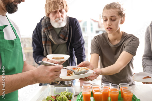Obraz na płótnie Volunteer giving food to poor people indoors