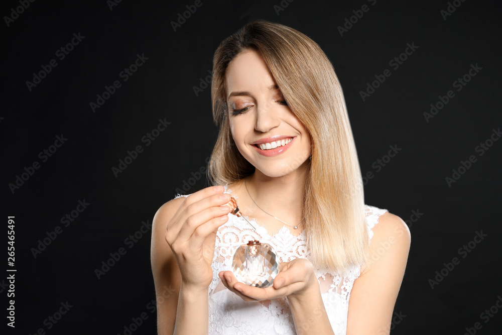 Beautiful young bride applying perfume against black background Beautiful young bride applying perfume against black background