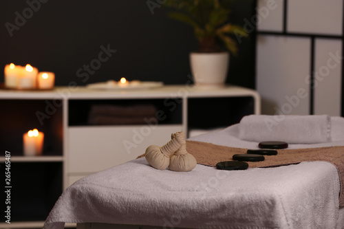 Herbal compresses and stones on massage table in spa salon