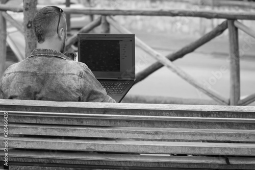 bw, Young man is sitting at the park and using laptop. concept of remote work, and finding information on the journey