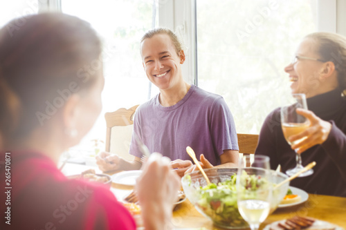 Smiling friends sit at the kitchen table. A joyful group of young people having fun together. 