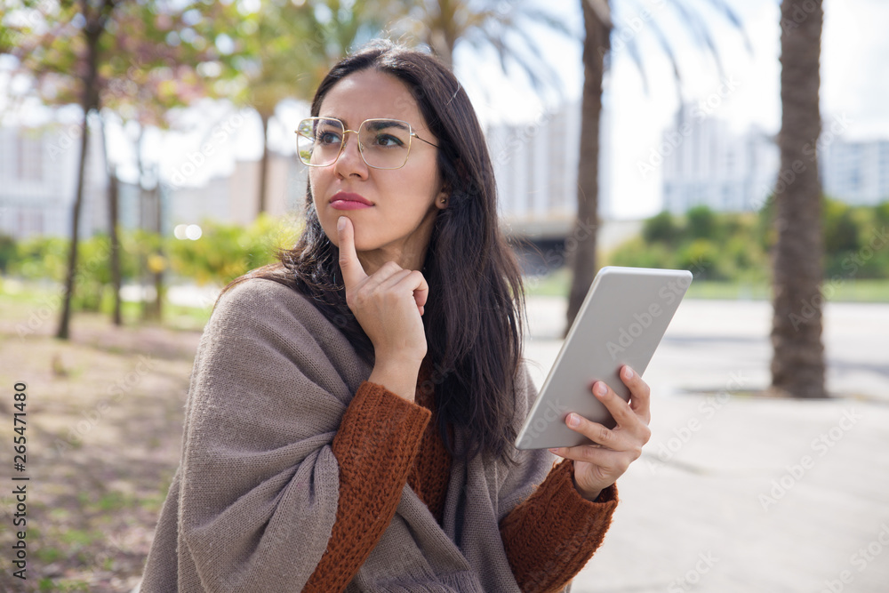 Pensive pretty woman using tablet computer outdoors Pensive pretty woman using tablet computer outdoors