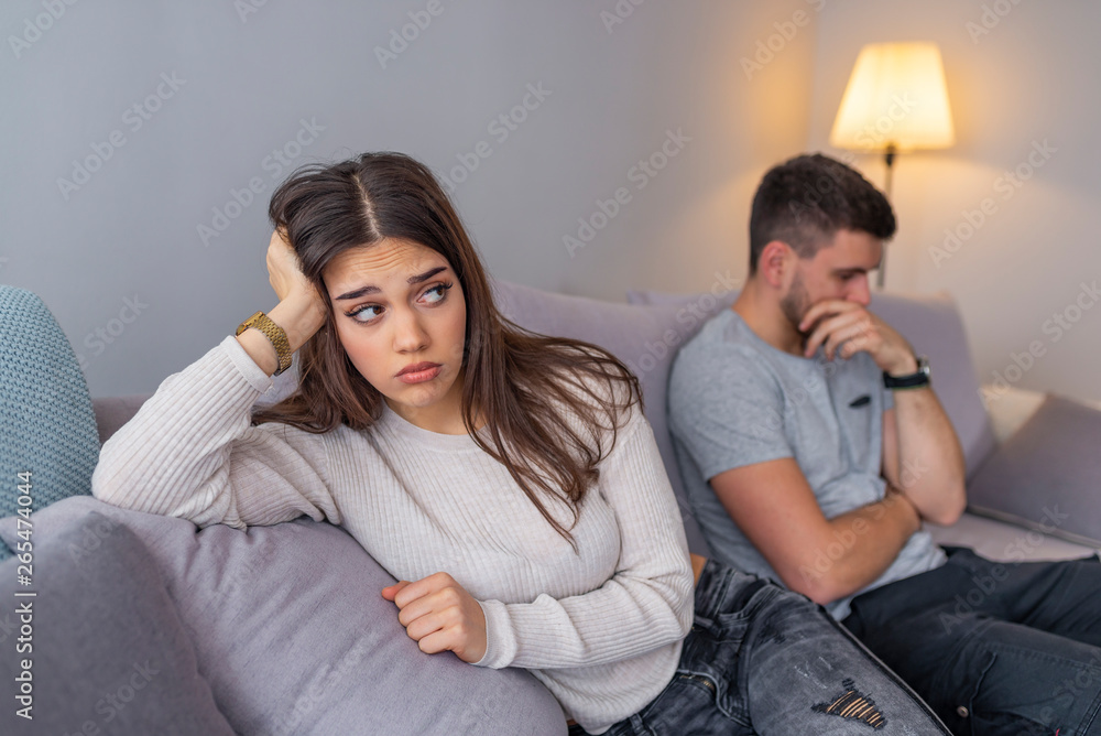 A man sitting on a couch is having an argument with his girlfriend who has her head turned away A man sitting on a couch is having an argument with his girlfriend who has her head turned away