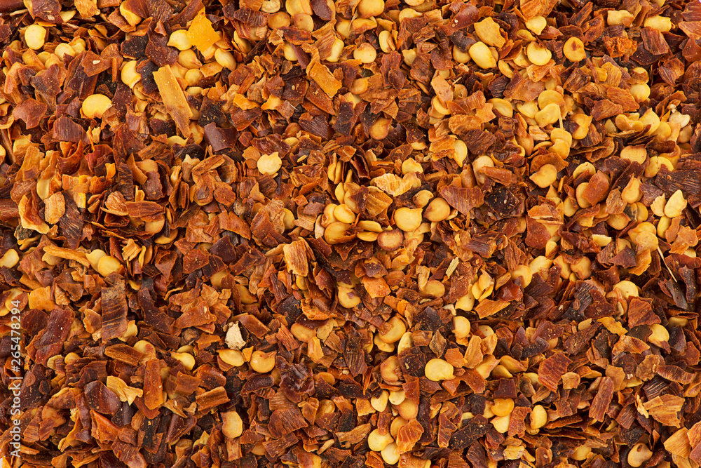 Top view on background texture of crushed red pepper flakes. Copy space for your text. Macro photography.