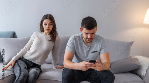 Cuadro en lienzo Jealous suspicious mad wife arguing with obsessed husband holding phone texting