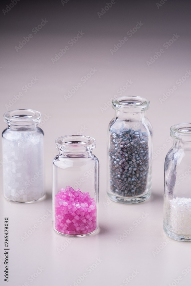 Varied colors beads in transparent bottles white background Varied colors beads in transparent bottles white background