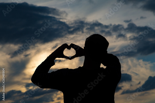 ein Mann bilden bei Sonnenuntergang am See ein Herz mit den Händen	