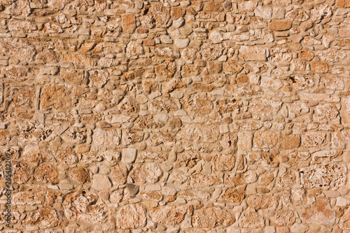 abstract brown, sandy, old wall of a stone house in the open air.