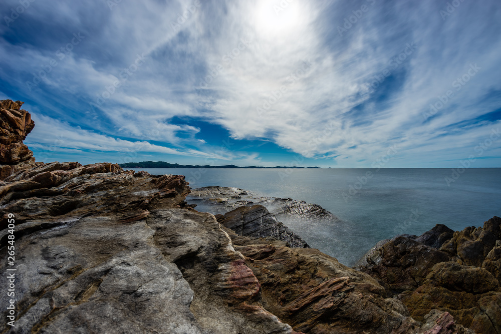 blue sky and Cloud   calm  ocean  in broad daylight  with the rocks in  foreground.