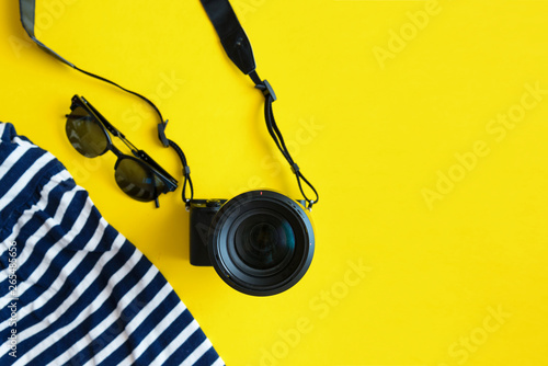 Flat lay traveler accessories on yellow background with blue dress, camera and sunglasses. Summer background concept