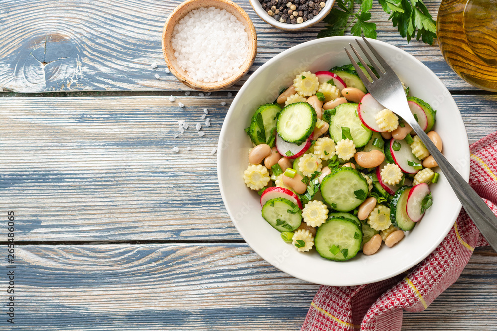 Healthy vegetable salad with cucumber, radish, beans, mini corn and herbs on rustic wooden background. Top view. Copy space. Healthy vegetable salad with cucumber, radish, beans, mini corn and herbs on rustic wooden background. Top view. Copy space.