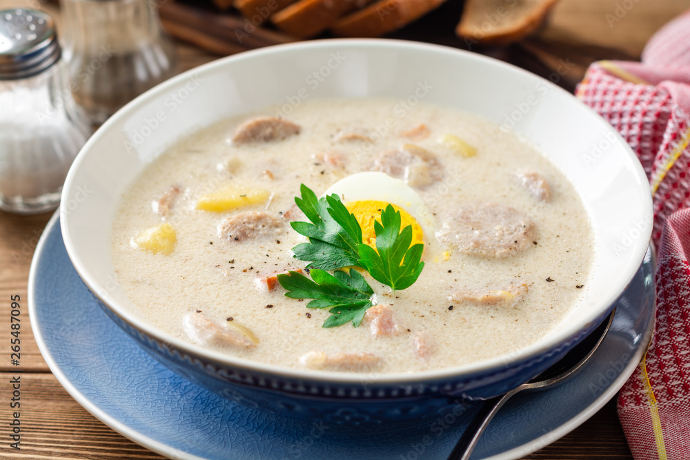 Traditional polish soup Zurek on wooden table. Selective focus.