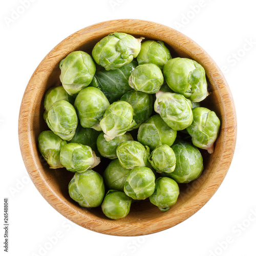 Fresh raw organic brussels sprouts in wooden bowl isolated on white. Top view, close-up.