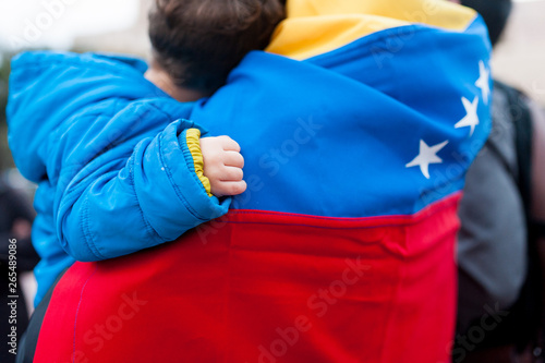 detail of little child hand on venezuelan flag as symbol of hope in future regime change, during march in support of Guaido government photo