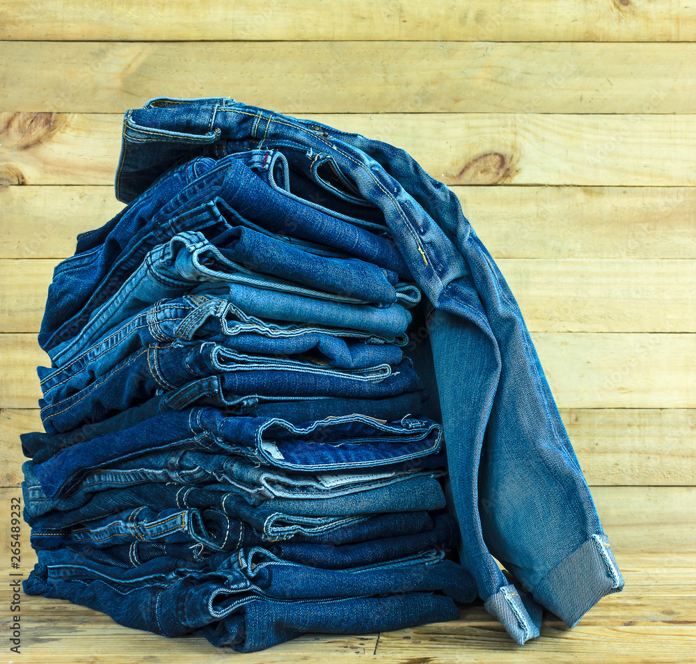  jeans stacked on wooden floor. blank background for design and text input.