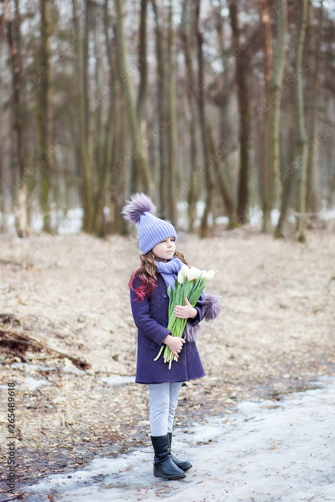 Cute little girl in the park with a bouquet of white tulips. Flowers as a gift for women's mother's day. March 8. Easter. Girl with a bouquet for happy mothers day. Makes a gift for your mom. Cute little girl in the park with a bouquet of white tulips. Flowers as a gift for women's mother's day. March 8. Easter. Girl with a bouquet for happy mothers day. Makes a gift for your mom.