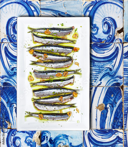 Fototapeta Naklejka Na Ścianę i Meble -  Anchovies cooked Basque Country style on a white plate over a tiled background.