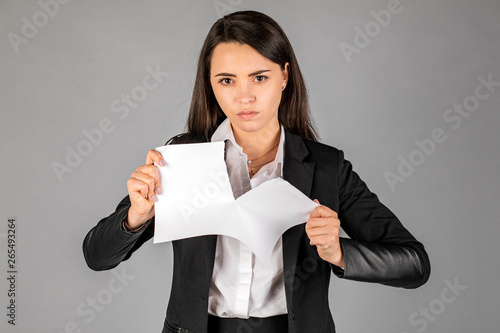 фотографія girl or businesswoman tearing a piece of paper on a gray background