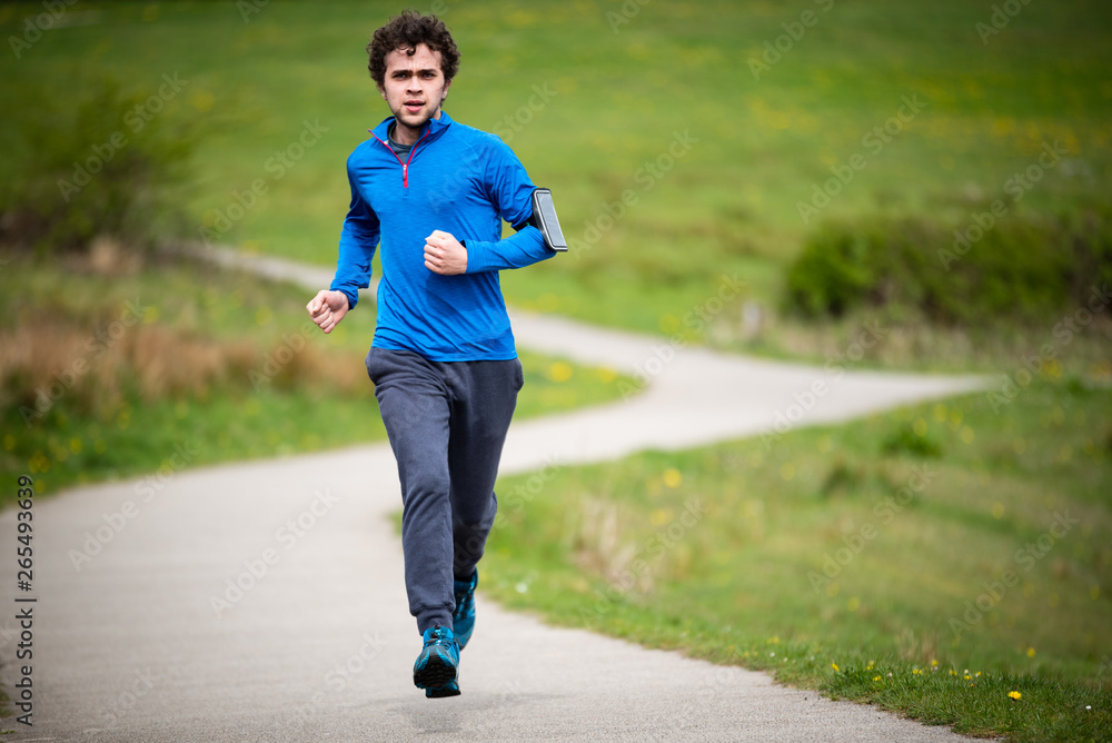 Young man in mid 20s exercising and keeping fit by running in a park Young man in mid 20s exercising and keeping fit by running in a park