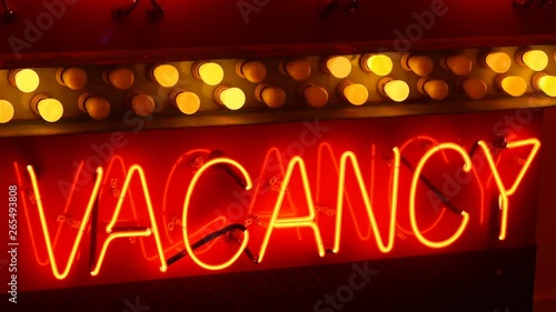 An illuminated, seamless looping, neon sign that reads, “Vacancy”