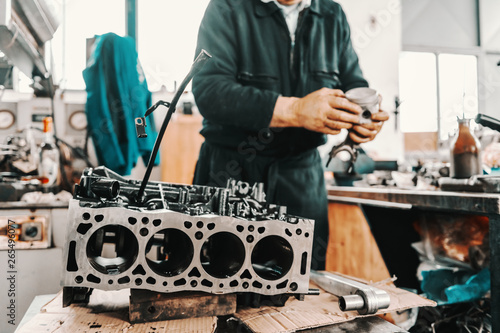 Auto mechanic adjusting cylinder from engine block at workshop.