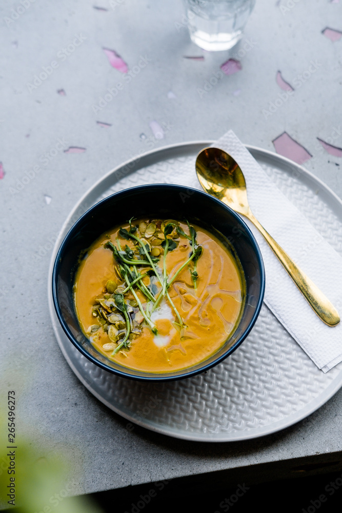 Pumpkin soup with golden spoon on gray stone background from above. Minimalism food photography concept, copyspace, top view, close up Pumpkin soup with golden spoon on gray stone background from above. Minimalism food photography concept, copyspace, top view, close up