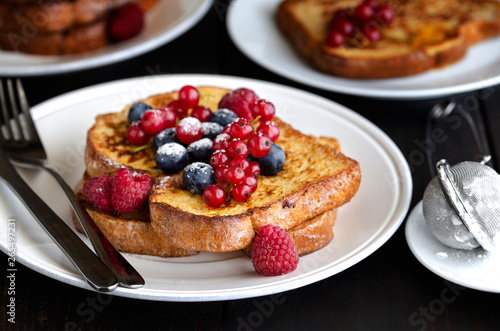 Traditional French toast with berries: blueberries, currant, raspberries  and icing sugar for perfect  sweet breakfast. Delicious dessert background.
