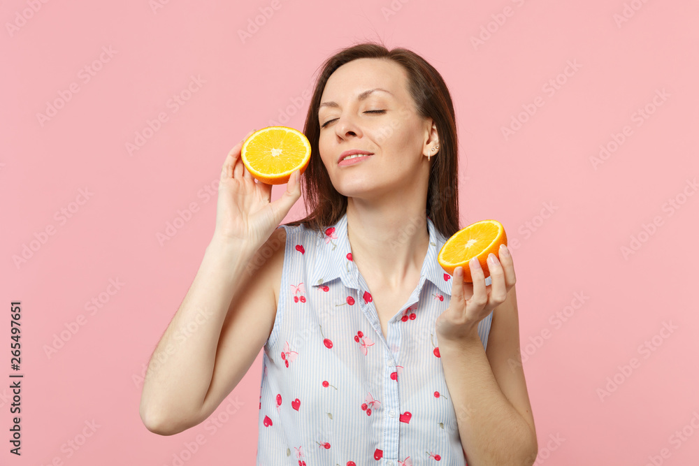 Pretty young woman in summer clothes keeping eyes closed holding halfs of fresh ripe orange fruit isolated on pink pastel background. People vivid lifestyle relax vacation concept. Mock up copy space. Pretty young woman in summer clothes keeping eyes closed holding halfs of fresh ripe orange fruit isolated on pink pastel background. People vivid lifestyle relax vacation concept. Mock up copy space.