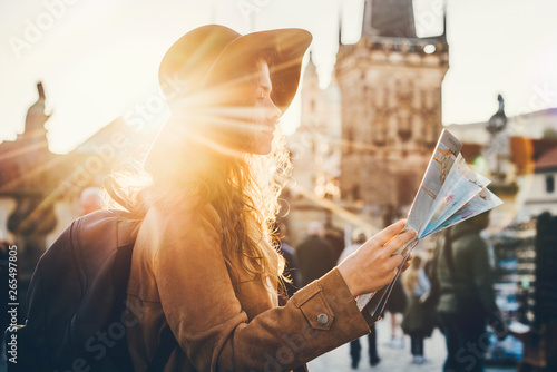 Girl with backpack looking at map. Girl visiting the sights Praha in holiday. Sun flare.