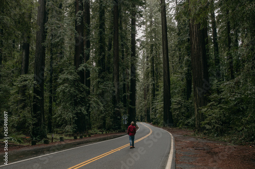 man in red flannel walking on road in forest