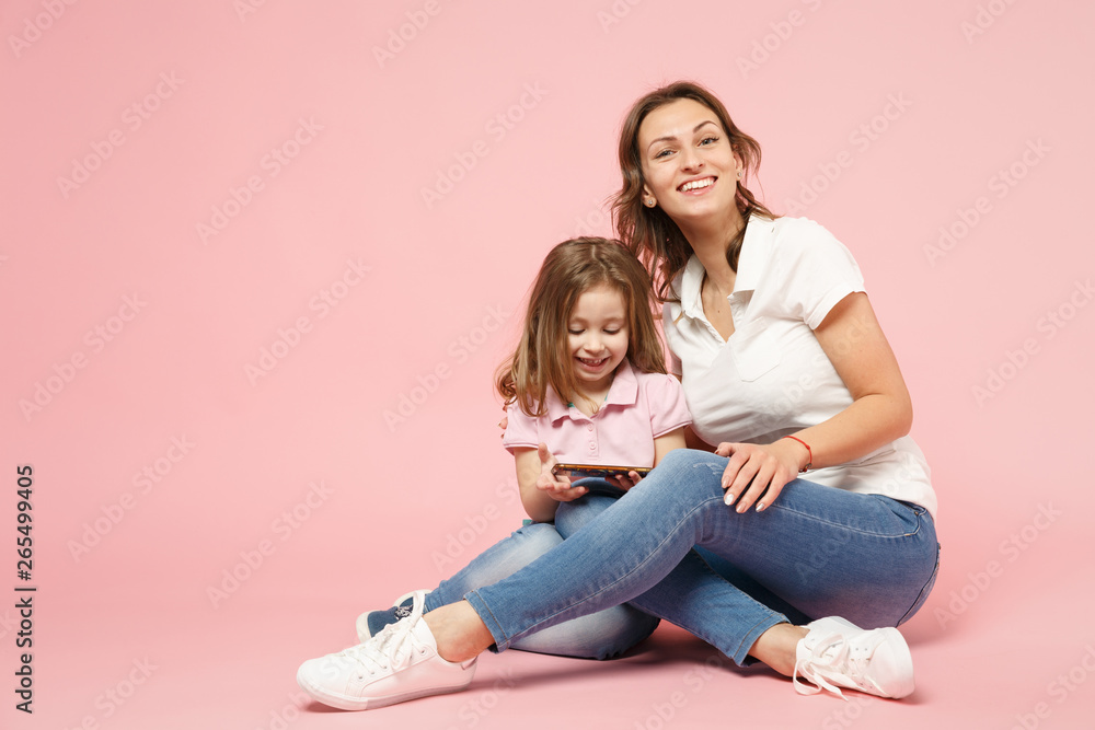 Woman in light clothes have fun with cute child baby girl. Mother, little kid daughter isolated on pastel pink wall background, studio portrait. Mother's Day, love family, parenthood childhood concept