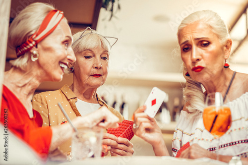 Upset long-haired old woman showing her cards during gambling game