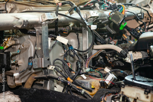 A large tangle of ravel multicolored wires from the car wiring lies in the cabin of dismantled car with connectors and plugs, a view through the window inside the battered car. Auto service industry © Aleksandr Kondratov