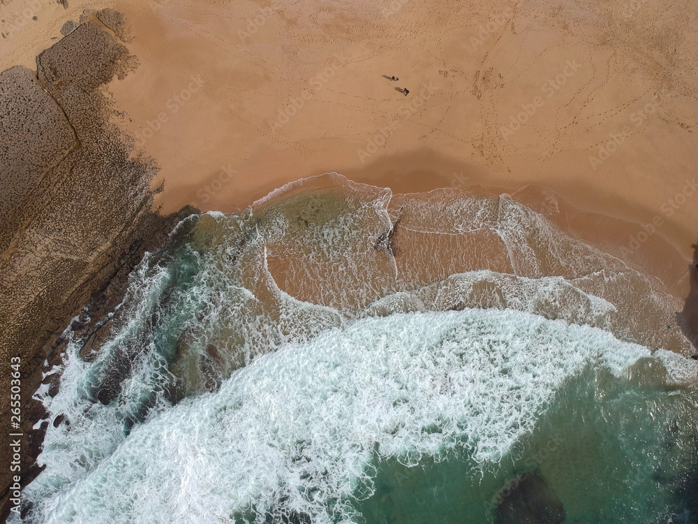 Aerial view of sandy beach with waves and clear ocean water. Drone photo