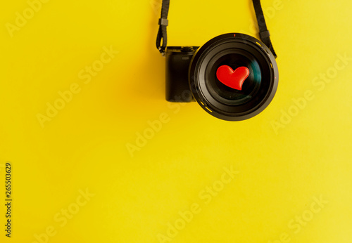 Flat lay of mirorless camera with lens and love red hearts on yellow background, engagement or couple wedding