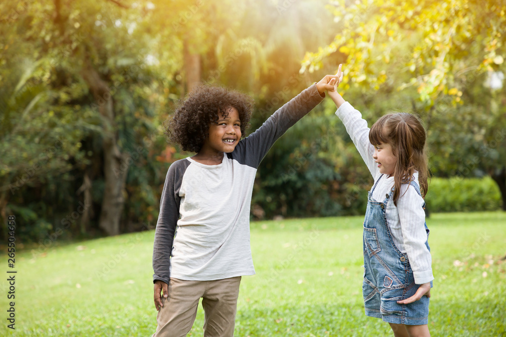 Fototapeta premium Children playing holding hands together in the garden in summer day