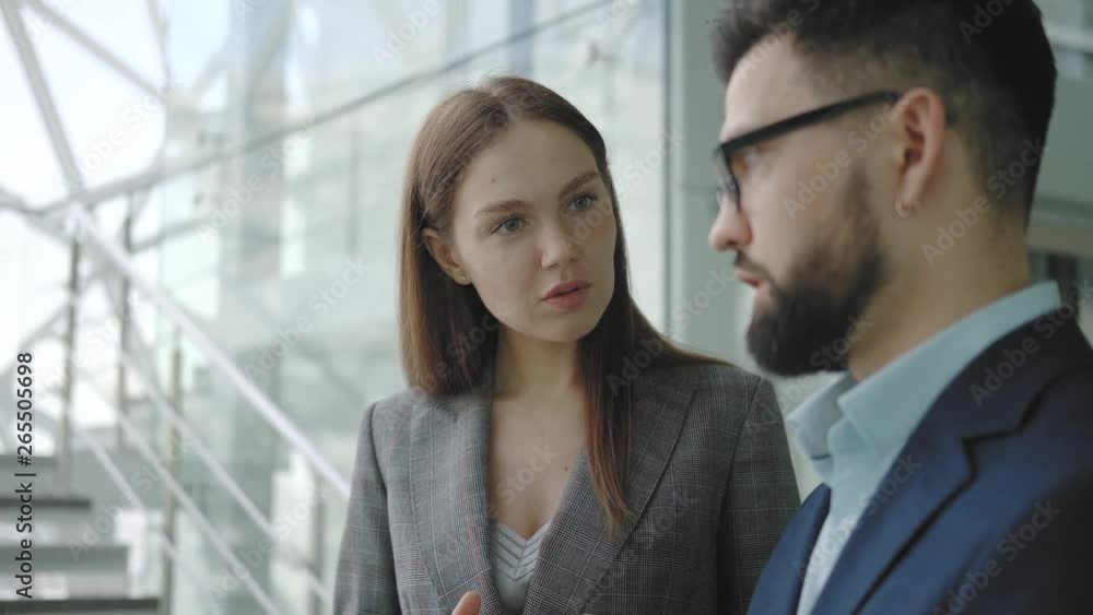 Beautiful young successful business woman in a suit communicates with a colleague or partner while standing in a bright high-tech business center against the background of the stairs. Beautiful young successful business woman in a suit communicates with a colleague or partner while standing in a bright high-tech business center against the background of the stairs.