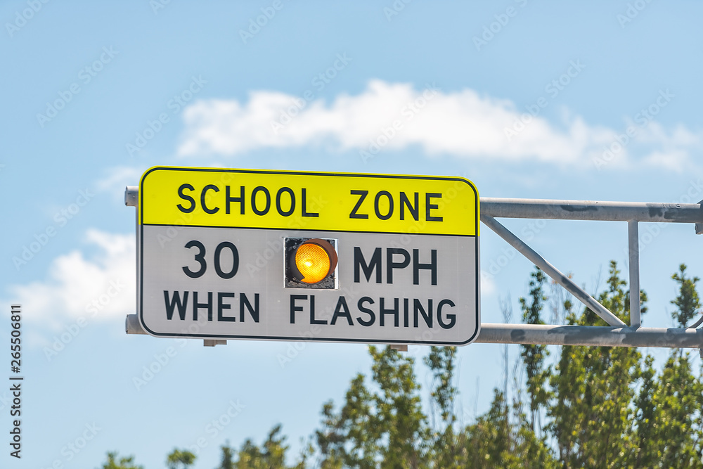 Fototapeta premium Public School Zone sign on road with 30 miles per hour when flashing text in Naples, Florida during day