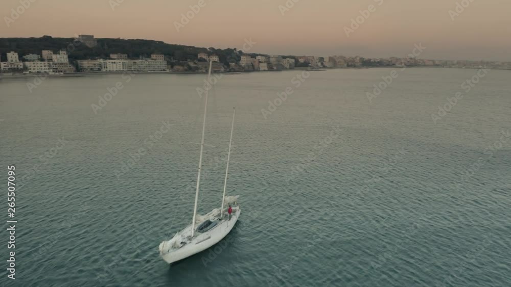 Aerial view of a moving sailboat near Nettuno in the evening, Italy Aerial view of a moving sailboat near Nettuno in the evening, Italy