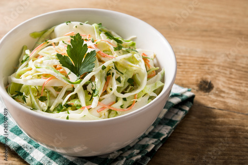 Coleslaw salad in white bowl on wooden table
