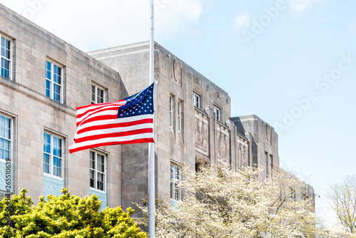 Asheville, USA closeup of American flag on pole waving in the wind by court house building architecture on sunny day