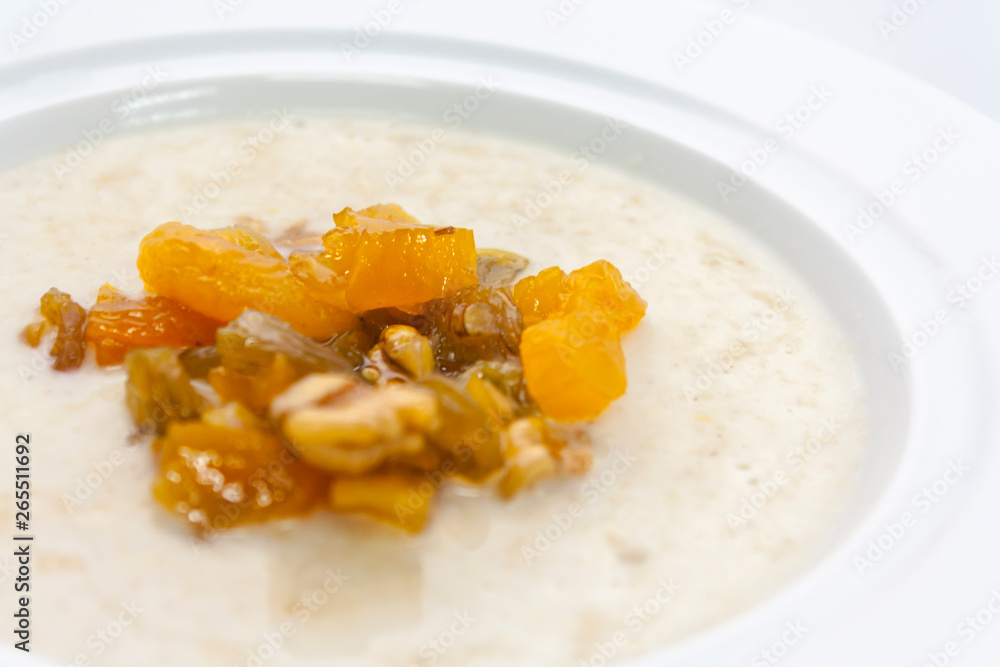 milk porridge with fruit, walnuts and butter in a white plate close-up milk porridge with fruit, walnuts and butter in a white plate close-up
