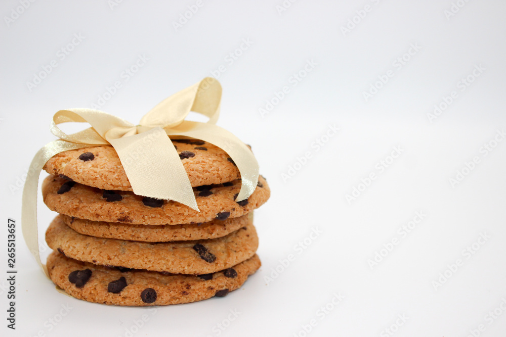 Oatmeal cookies with chocolate drops, tied with a golden ribbon, isolated on white background